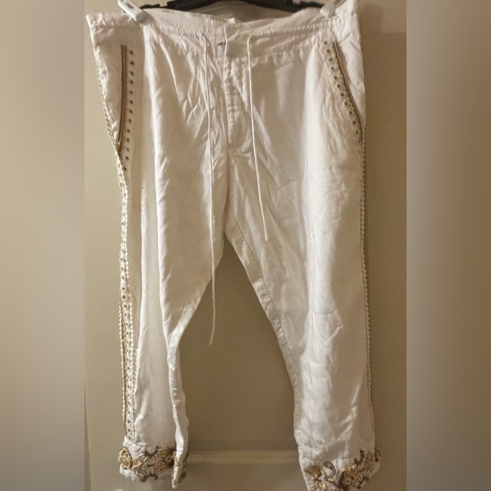 Cream pants with embellishments to sides, pockets and hems.